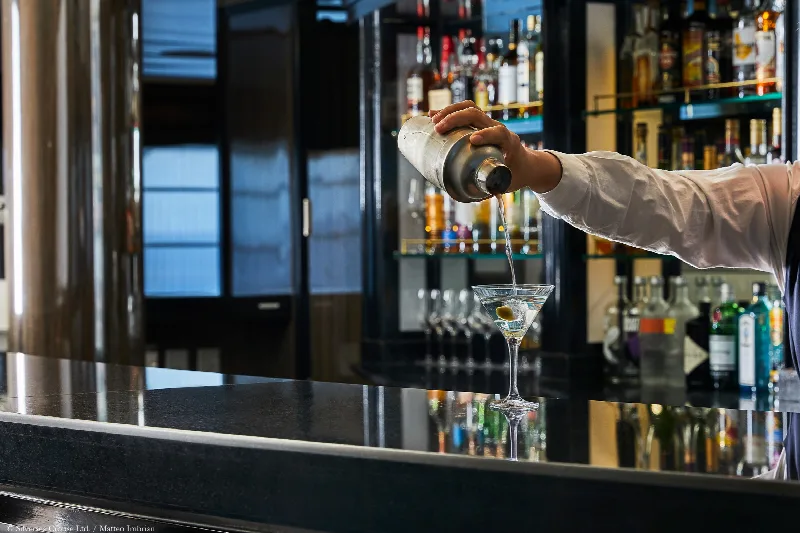 Ein Barkeeper gießt einen Martini an der Bar eines Kreuzfahrtschiffs ein