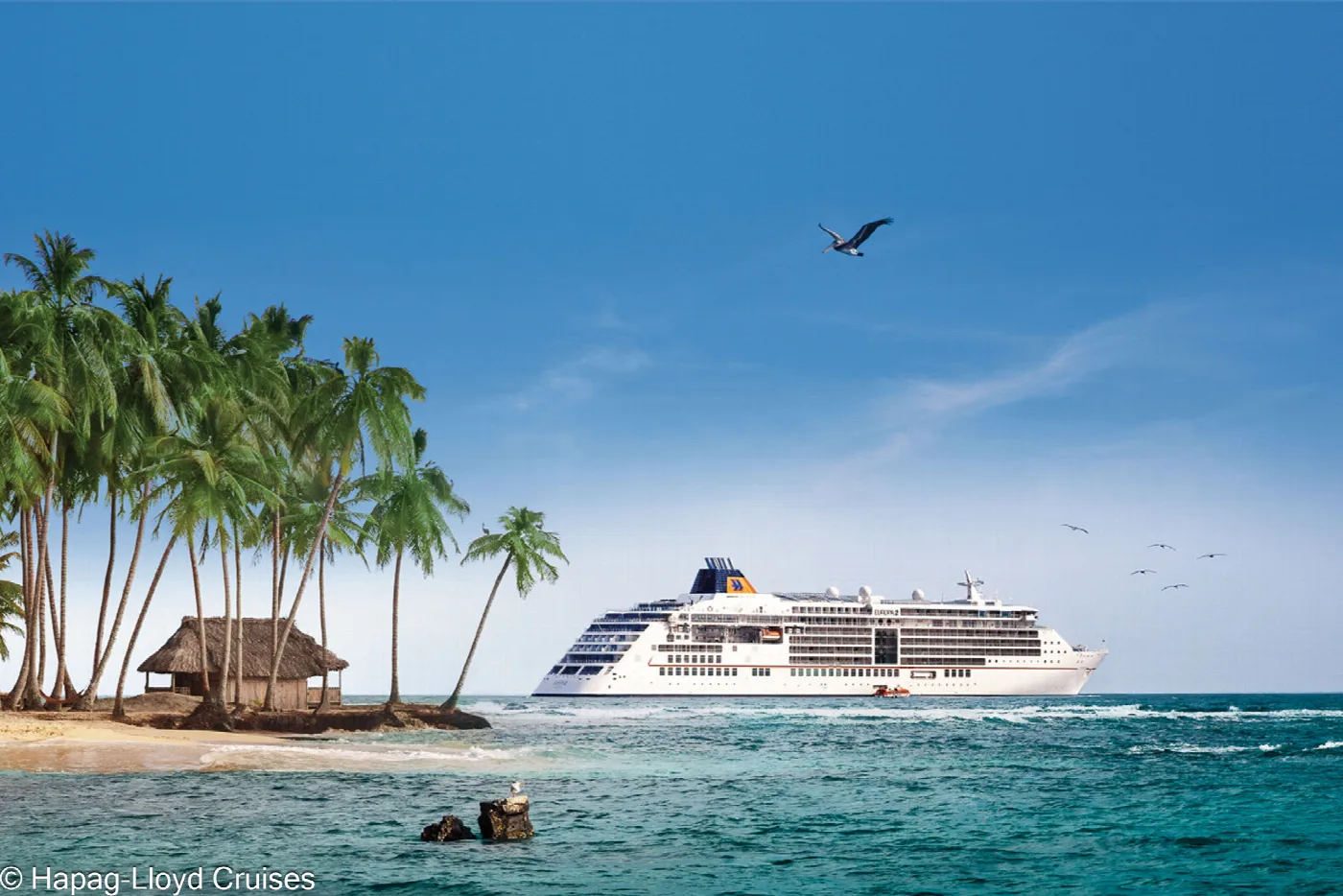 Ein kleines Kreuzfahrtschiff vor einer Palmeninsel mit Strohhütte in San Blas, Panama