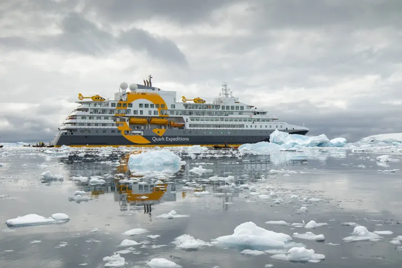 Das Expeditionsschiff Ultramarine von Quark Expeditions mit zwei Hubschraubern an Deck zwischen Eisbergen in der Antarktis
